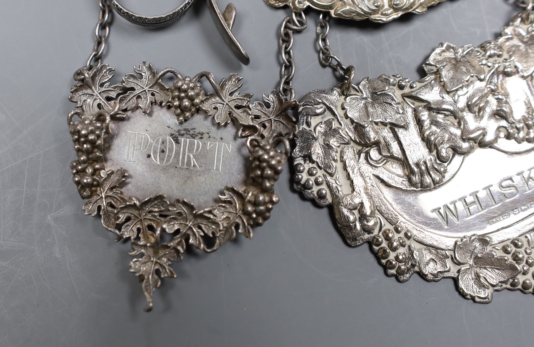 Seven assorted modern silver wine labels, including Whisky and Rum and a similar ceramic label.